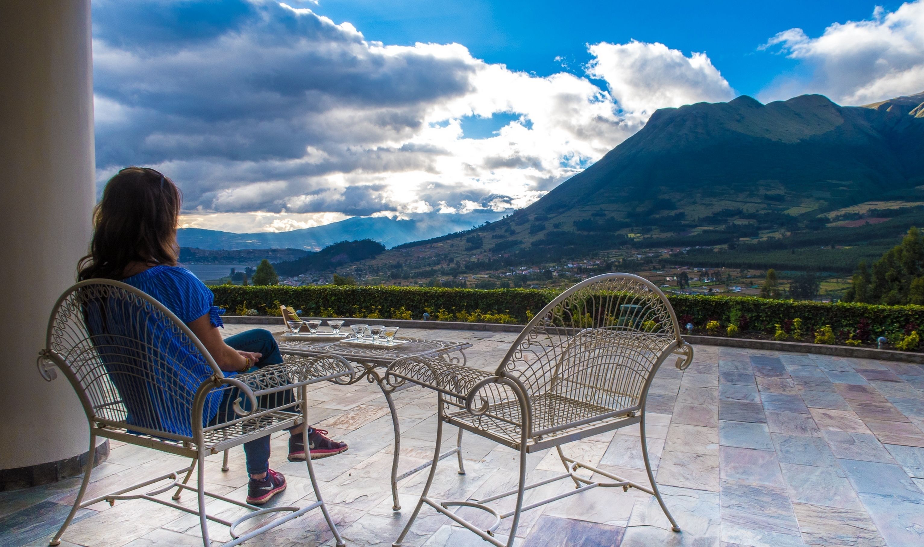 A person seated at a table with a scenic mountain view.