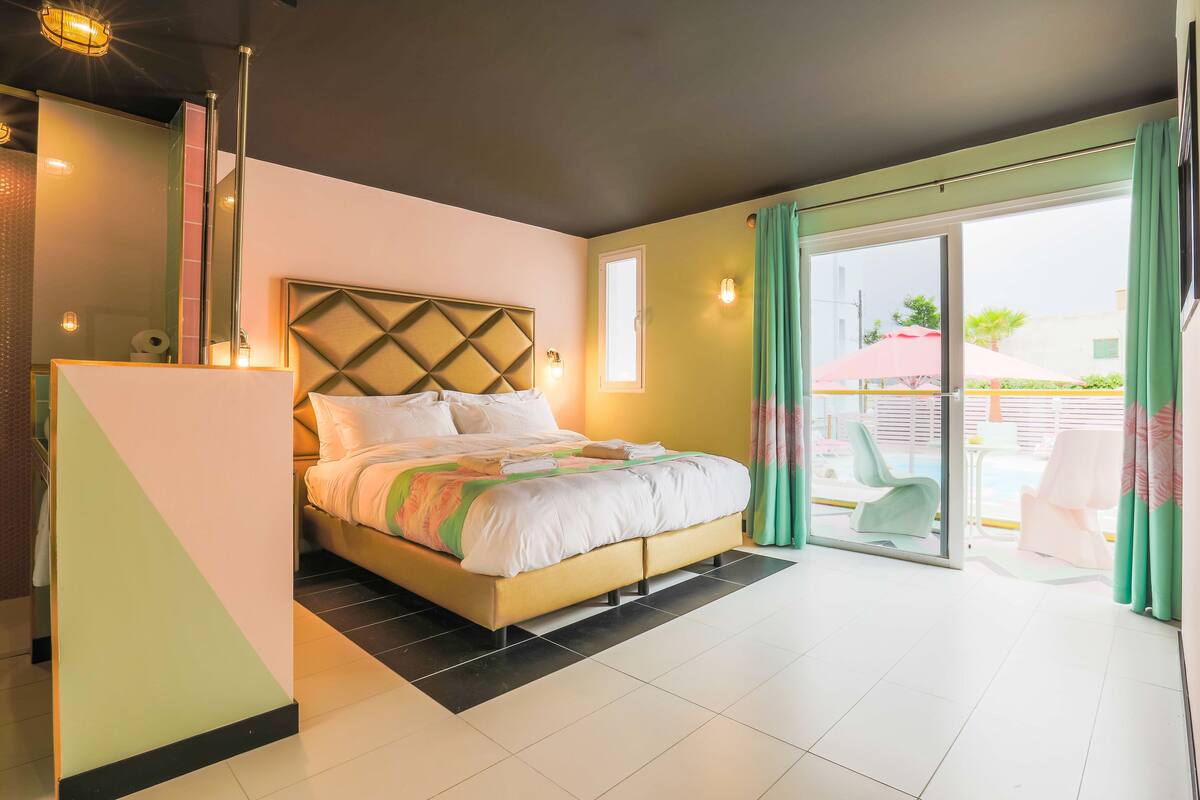 A modern hotel room with a bed, a small table, and a view of the outside.