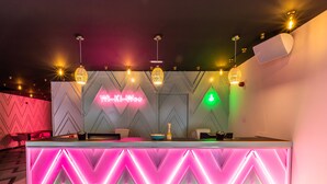 Un'accoglienza moderna con insegna al neon, un bancone bar e illuminazione d'ambiente.
