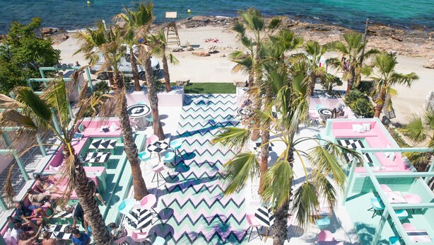 Un resort sulla spiaggia con aree salotto all'aperto, palme e vista sull'oceano.