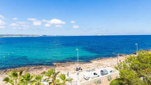 Una zona costiera con una spiaggia rocciosa, un camper parcheggiato e una vista aperta sul mare.