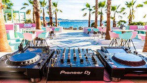 Attrezzatura per DJ con marchio Pioneer DJ su una terrazza affacciata sul mare e sulle palme.