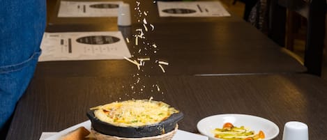 A person sprinkling cheese over a dish in a restaurant setting.