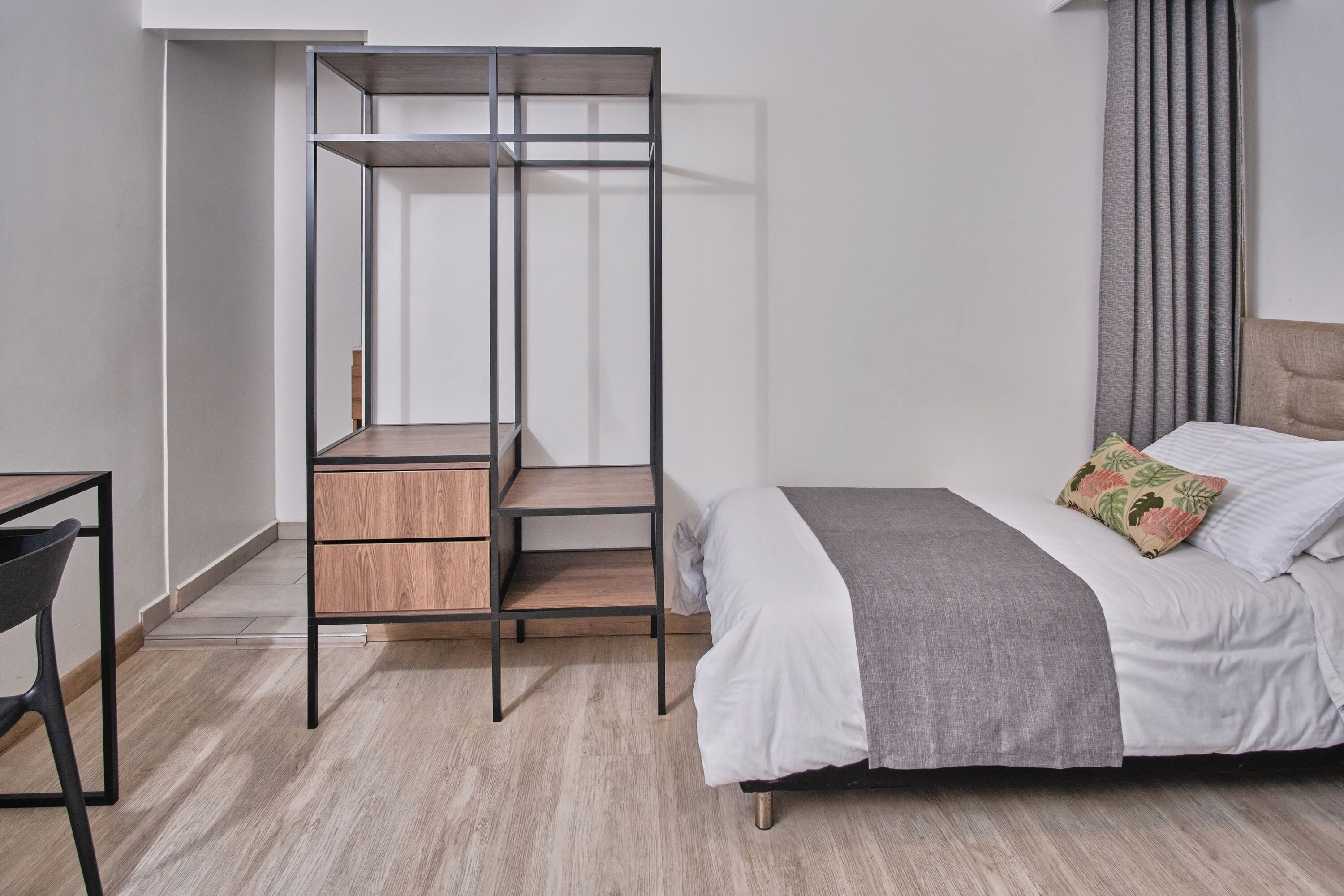 A bedroom with a bed, a desk, and a wardrobe.