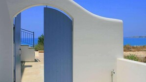A white building with a blue door and a view of the sea. - Blue Coral Beach Villas (Paphos)