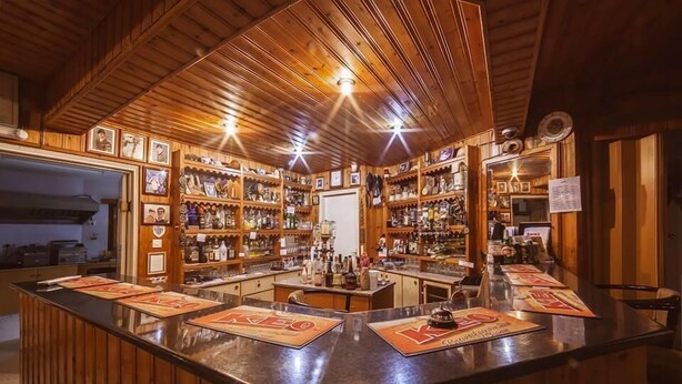 En bar med trævægge og -loft, med en disk med menukort og et udvalg af flasker.