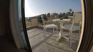 En balkon med bord og stole, et frit udsyn over det omkringliggende landskab, og et flisegulv.
