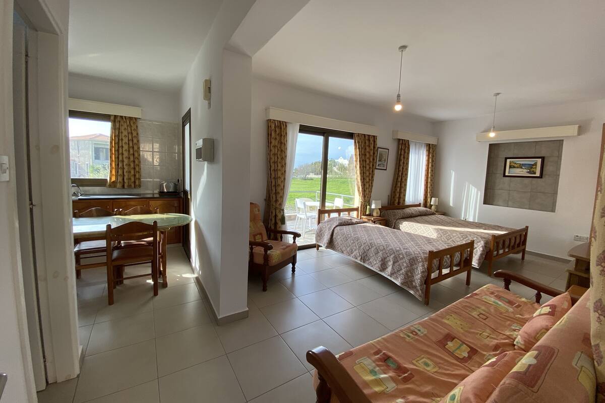 Une chambre d’hôtel avec un balcon, un coin repas et un lit avec une literie à motifs.