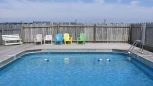 A rectangular swimming pool with a wooden deck and a wooden fence in the background. - Joyce's Motel & Cottages (St. Peters)