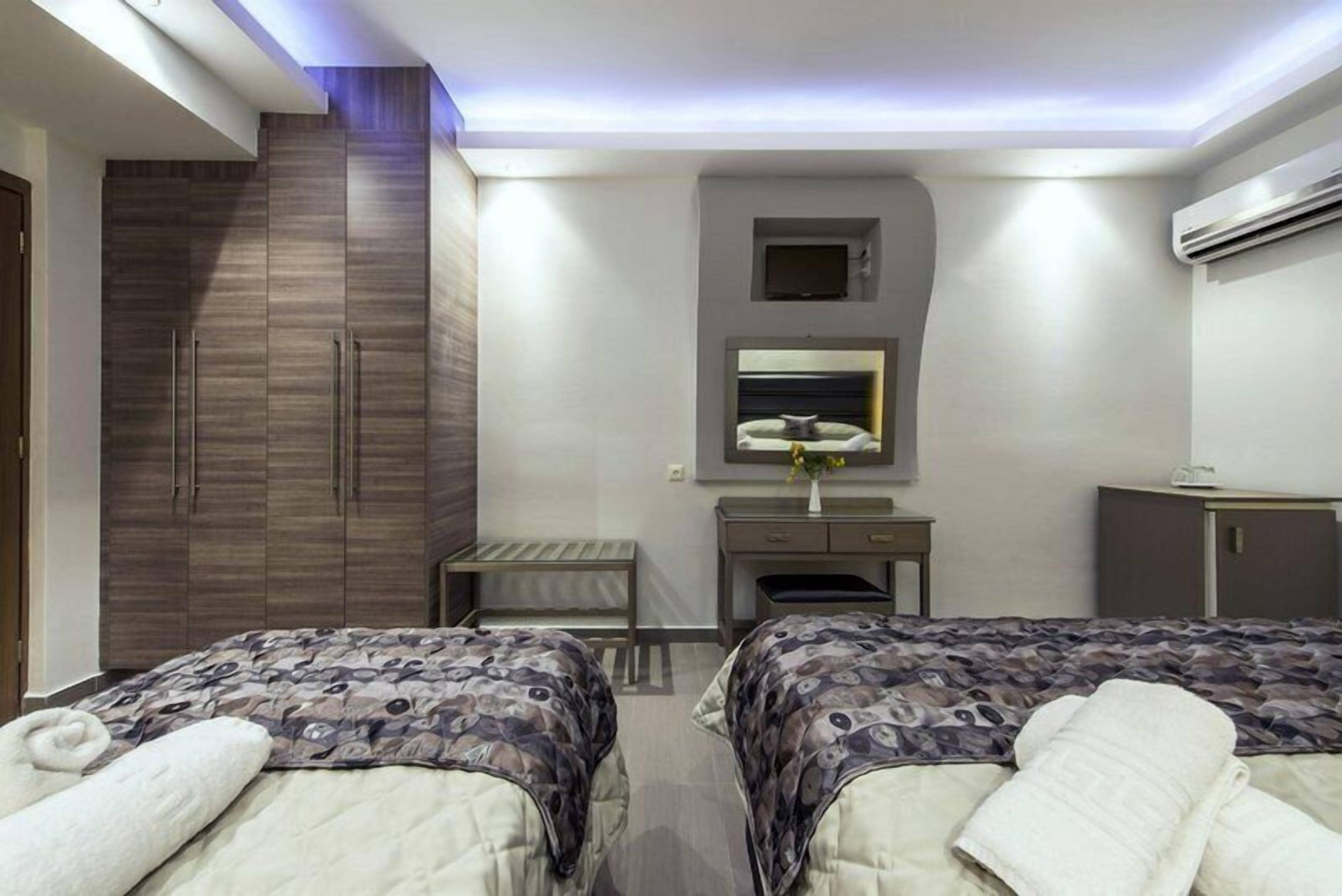 Ein Hotelzimmer mit zwei Betten, einem Schreibtisch, einem Kleiderschrank und einer kleinen Sitzecke.