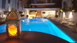 Een seizoensgebonden buitenzwembad en ligstoelen