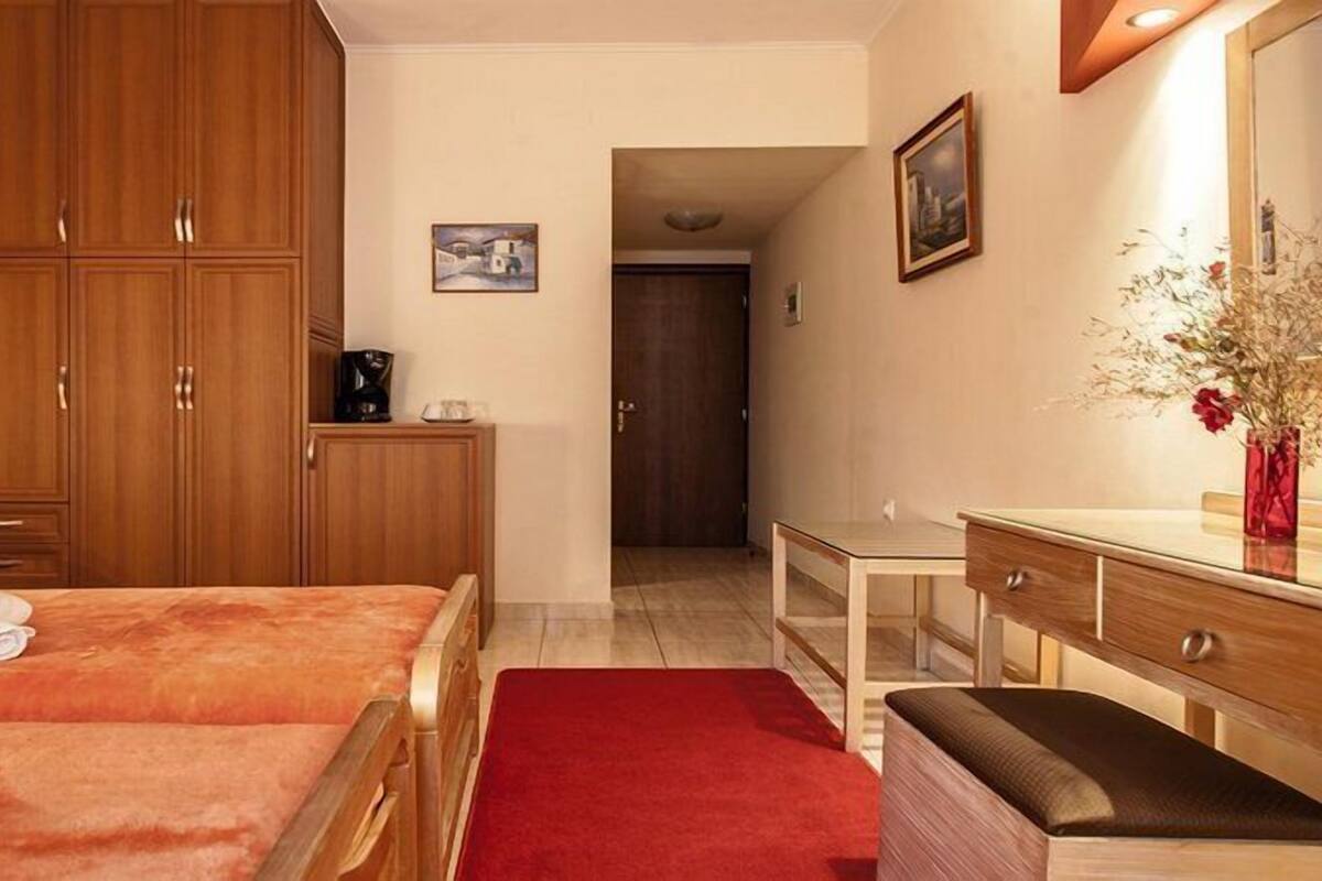 A hotel room with two beds, a desk, a chair, a dresser, and a mirror.