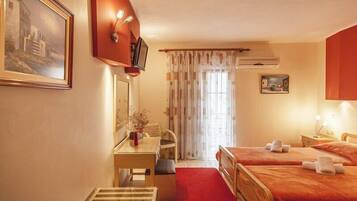 A hotel room with two beds, a desk, a chair, a mirror, and a window with curtains.
