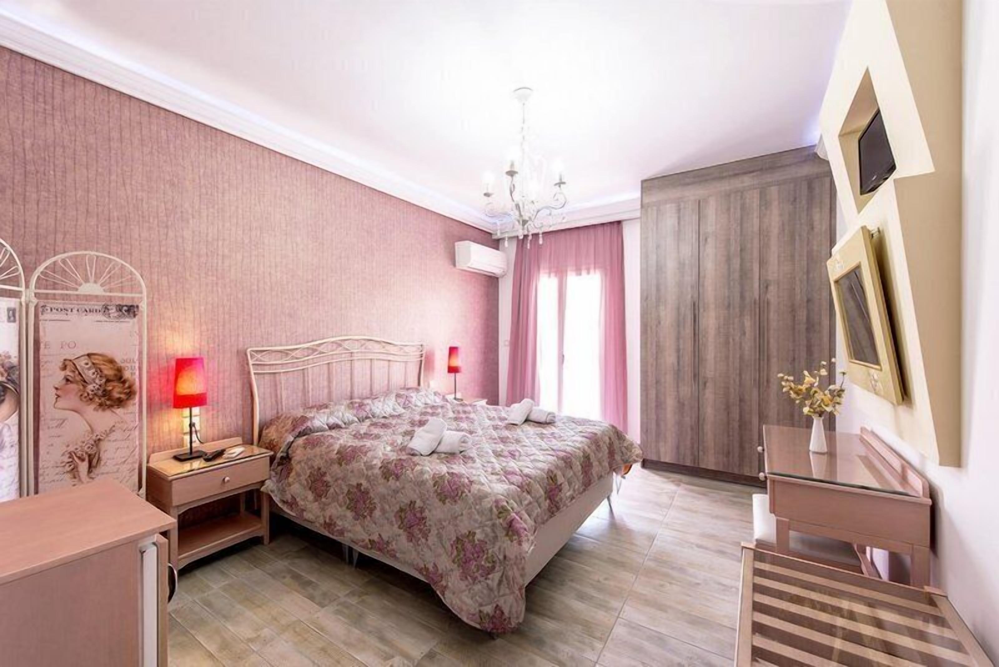 Une chambre à coucher comprenant un lit, une table de chevet, une lampe, une commode et un bureau avec un vase.