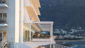 Un edificio moderno con piscina, balcón y vistas al mar y a las colinas.