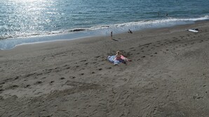 Una playa con cielo despejado y mar tranquilo.