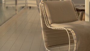 Un área de estar interior moderna con sillones acolchados y barandilla de vidrio.