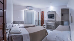 Ein Hotelzimmer mit zwei Einzelbetten, einem an der Wand befestigten Fernseher, einem kleinen Schreibtisch und einem Kleiderschrank.