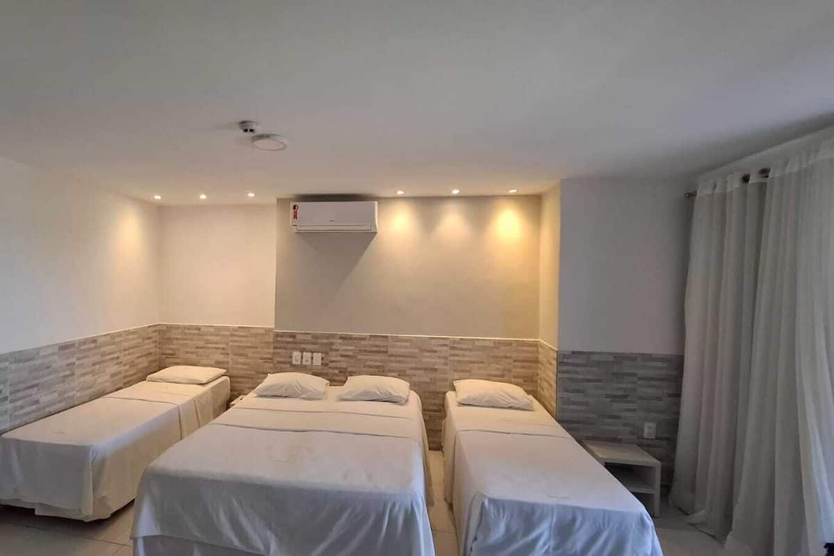 Ein Hotelzimmer mit zwei Einzelbetten, einem kleinen Tisch, einem Stuhl und einem Fenster mit Vorhängen.