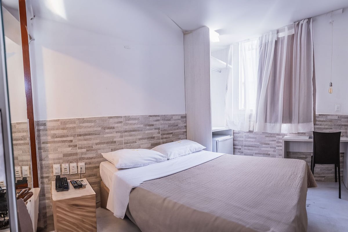 Ein modernes Hotelzimmer mit einem großen Bett, einem Schreibtisch und einer Duschkabine.