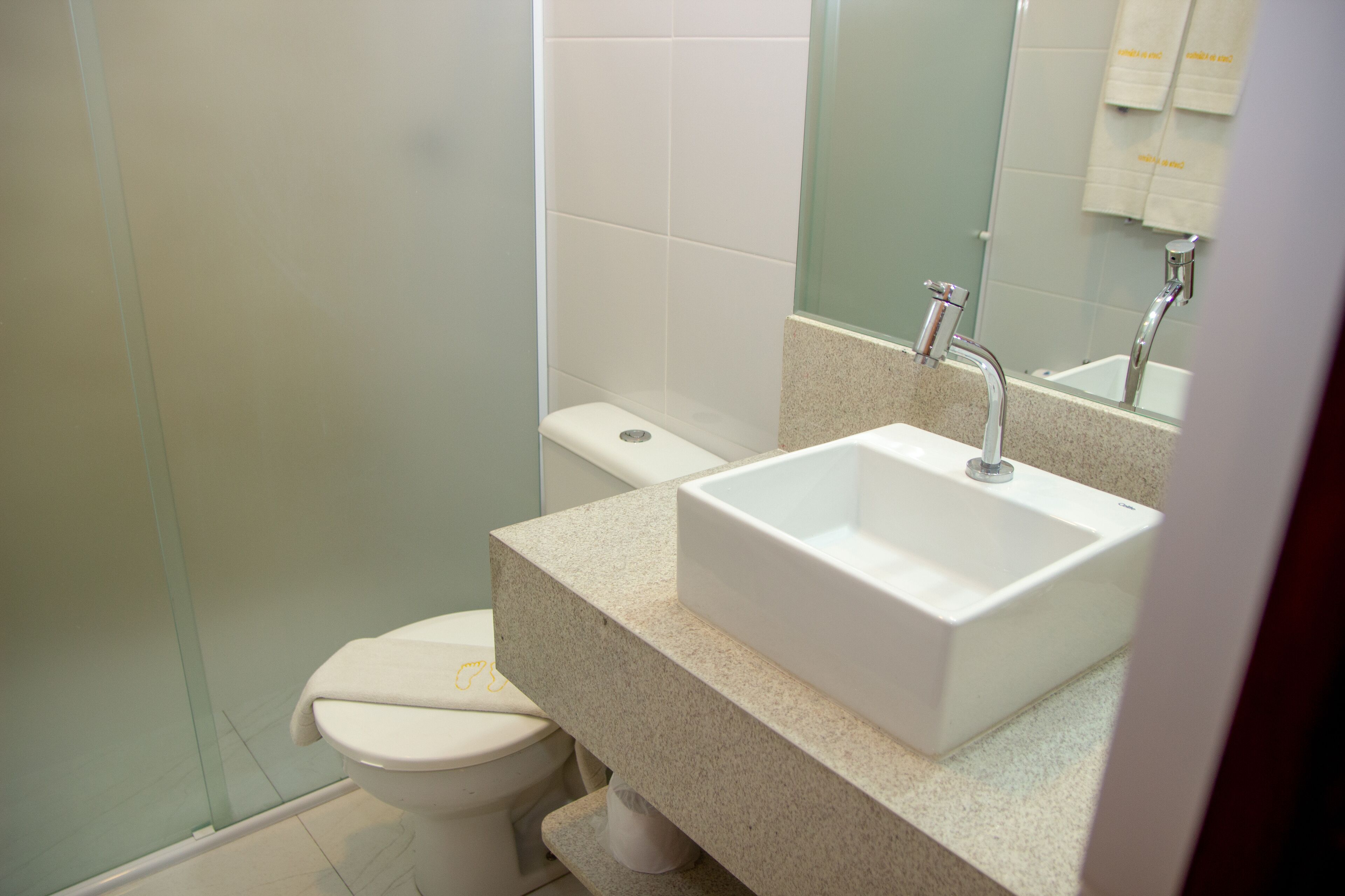 A bathroom with a white toilet, a sink with a mirror above it, and a shower area.