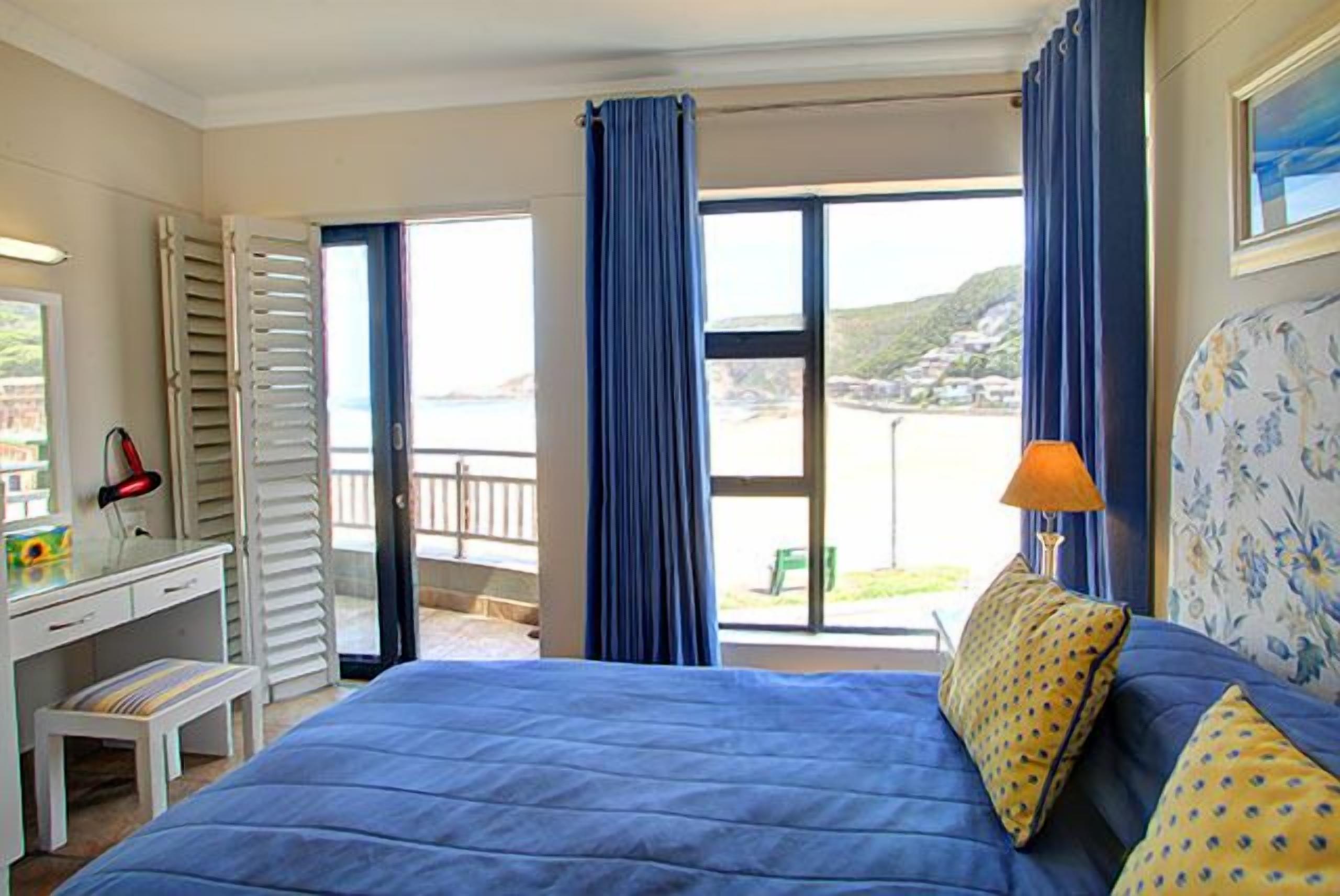 Une chambre avec un lit, un bureau et une vue sur la mer.