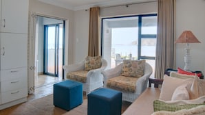 A spacious living area with a view of the sea, featuring two armchairs, a sofa, and a coffee table. - Makarios on Sea (Herolds Bay)