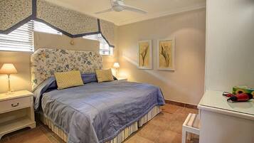 Ein Schlafzimmer mit einem Bett, Nachttischen, einem Deckenventilator und Kunstwerken an der Wand.