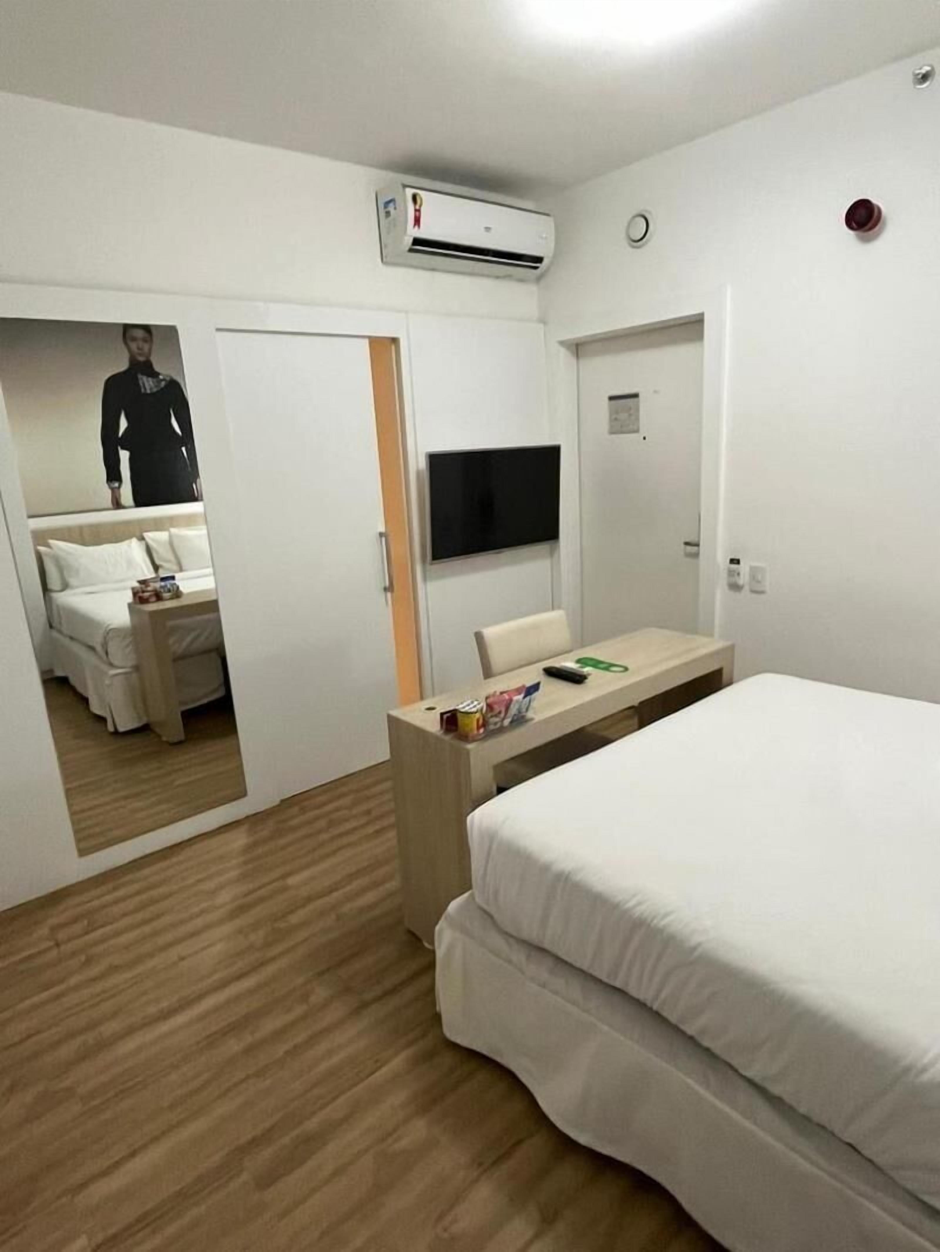 Une chambre d’hôtel équipée d’un lit, d’un bureau, d’une télévision et d’un climatiseur.