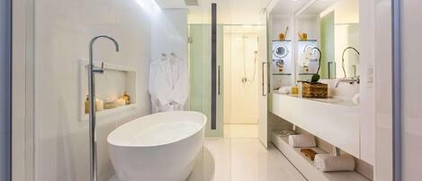 A modern bathroom with a freestanding bathtub, a glass-enclosed shower, and a vanity with a large mirror and towel storage.