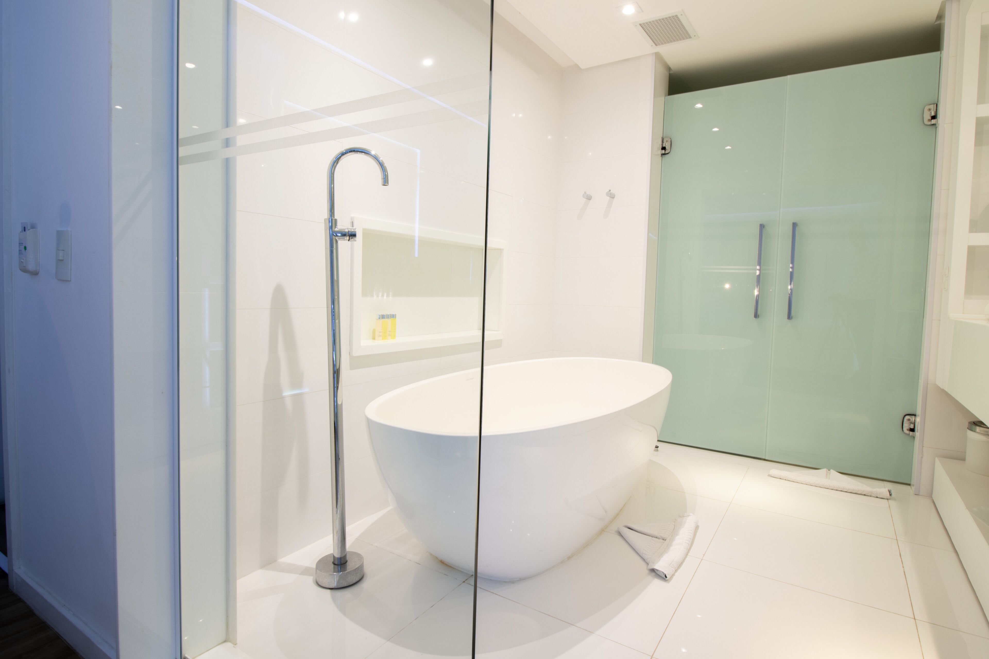 Une salle de bain moderne avec une baignoire sur pieds, une douche à parois de verre et un meuble-lavabo blanc.