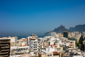 A cityscape with high-rise buildings, a prominent mountain in the background, and a clear sky. - Samba Bossa Nova Ipanema (Rio de Janeiro)