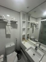 Un baño con inodoro, lavamanos, espejo y toallero.