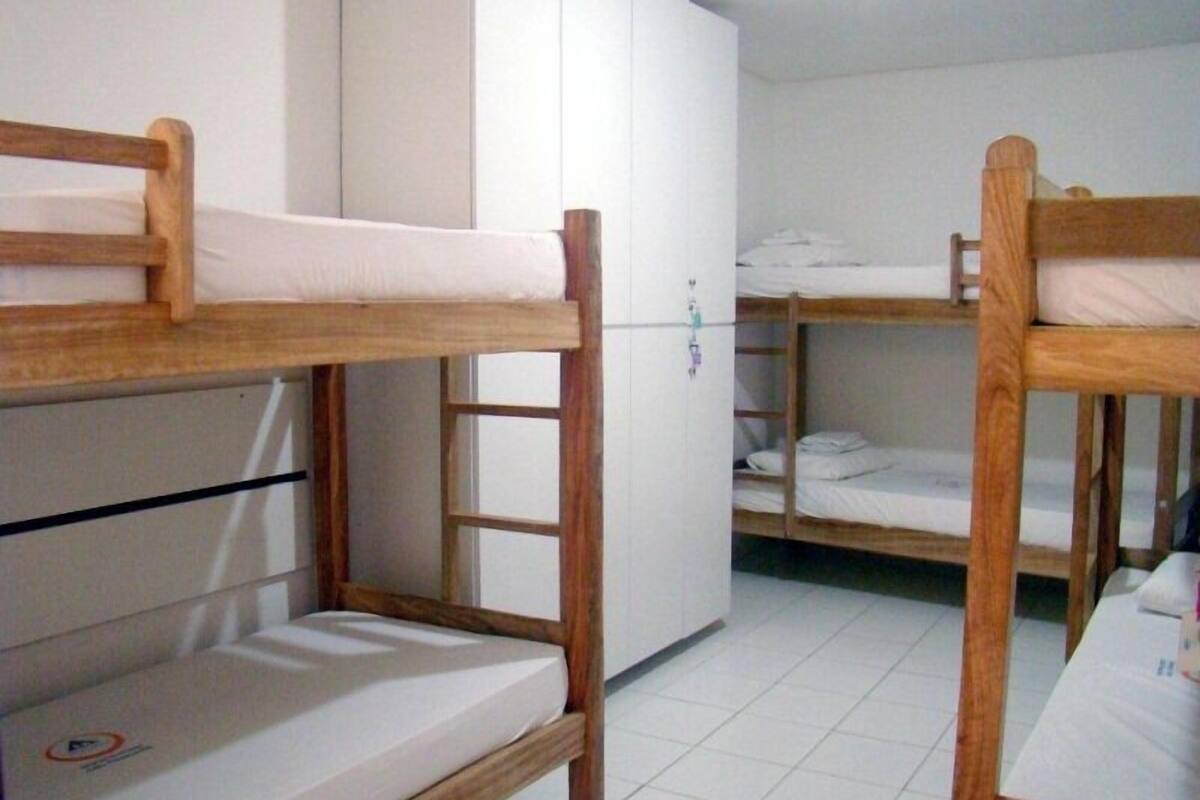 A dormitory room with bunk beds, a wardrobe, and a tiled floor.