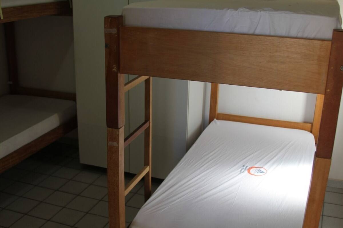 A bunk bed with a wooden frame and white bedding.