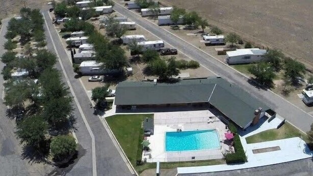 Eine Vogelperspektive eines Campingplatzes mit Wohnmobilen, einem Schwimmbad und einem großen Gebäude mit geneigtem Dach.