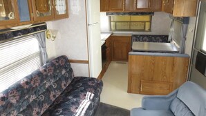 Eine gemütliche Küchenzeile in einem Wohnmobil mit Holzausbau, integriertem Herd und einer kleinen Sitzecke.