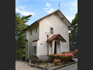 A two-story building with a gabled roof, a front porch, and a mailbox.
