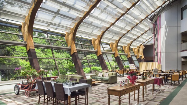Ruime binnenzone met een hoge plafond en grote ramen, met tafels en stoelen voor dineren of gezellig samenzijn.