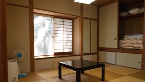 Een traditionele Japanse kamer met tatami vloerbedekking, een verschuifbaar shoji-scherm, een tafel en een waaier.