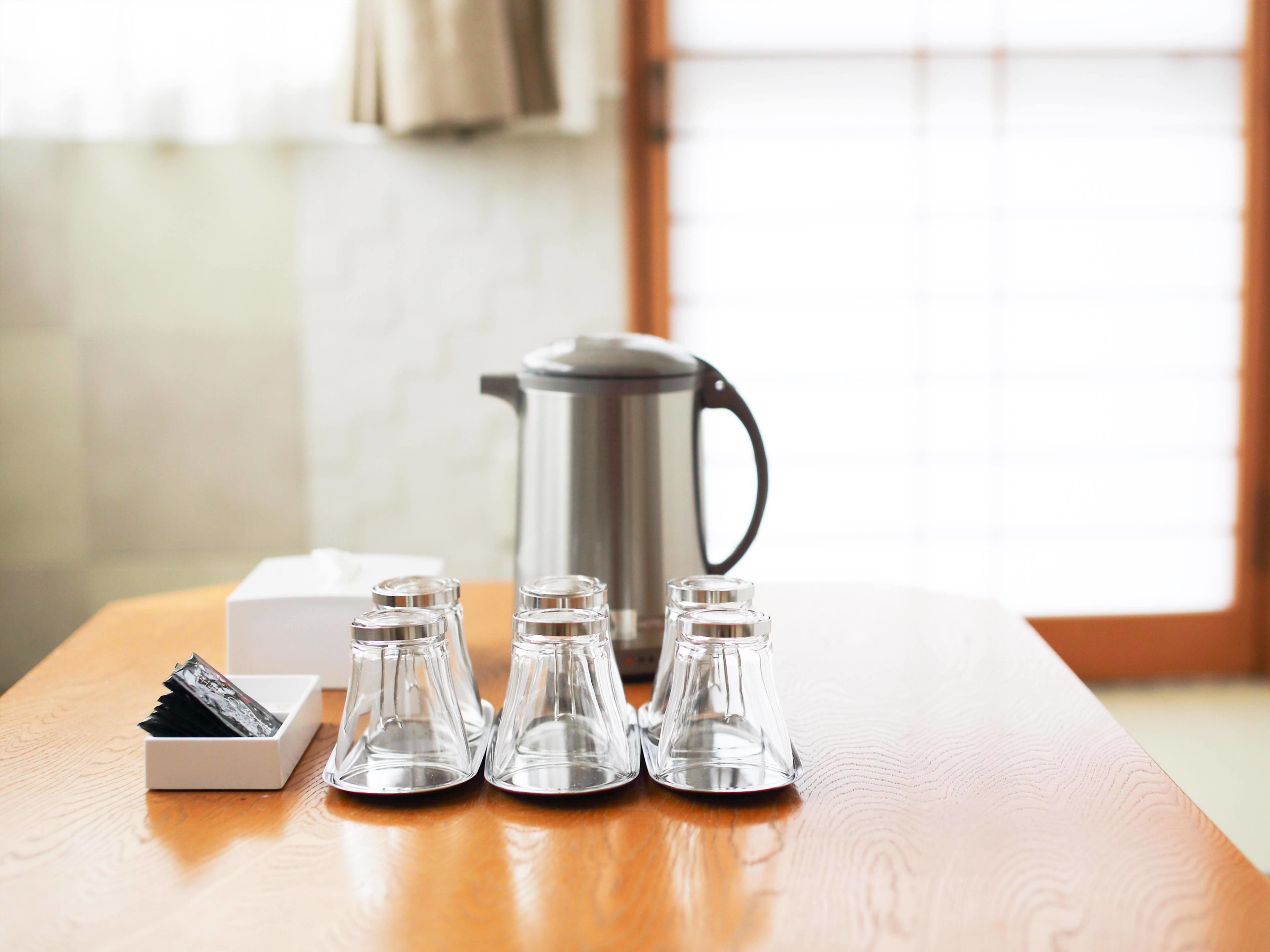 A wooden table with a coffee maker, salt and pepper shakers, and a box of sugar packets.