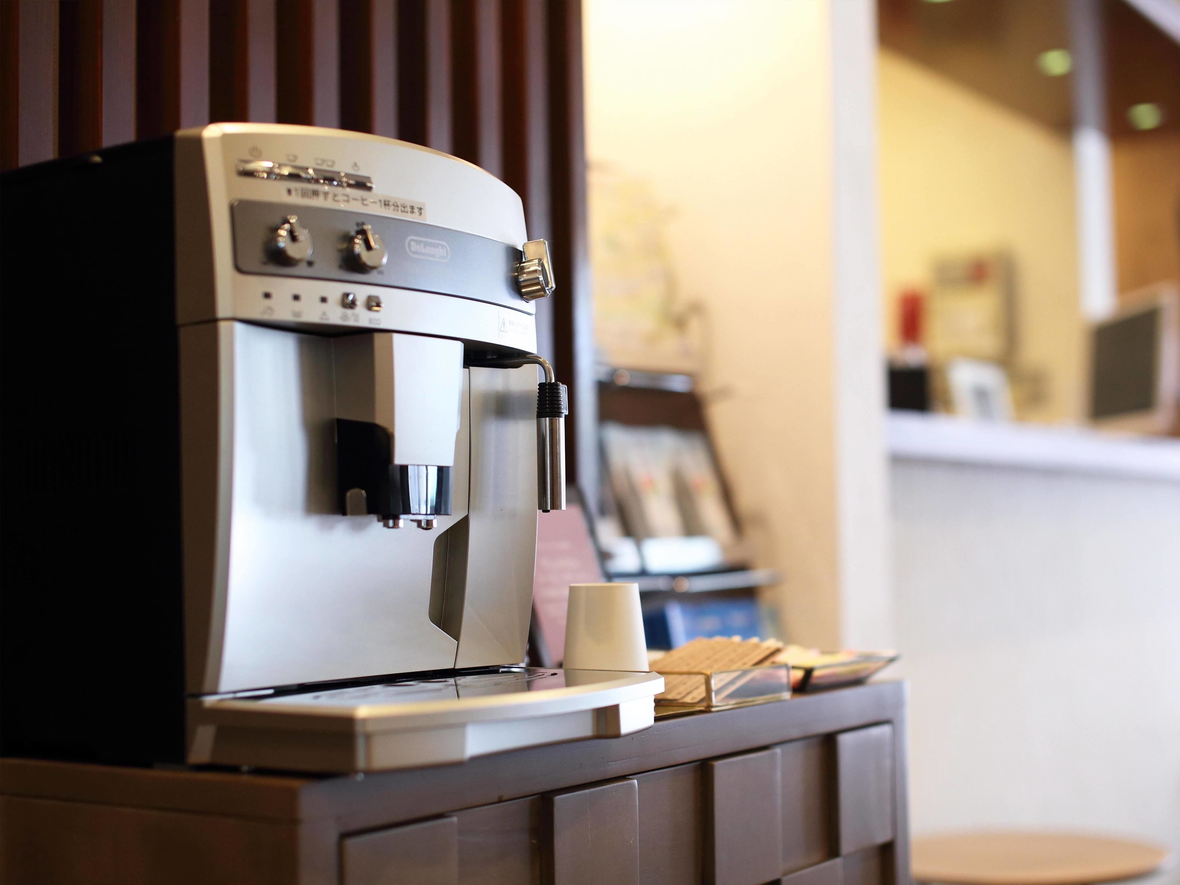 A coffee machine with a milk frother and a small cup on a counter.