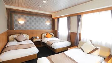 A hotel room with two beds, a nightstand with a lamp, a wall-mounted light, and a window with curtains.