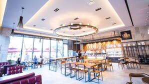 A modern cafe with a central bar, seating areas, and large windows. - J Square Hotel (Jinju)