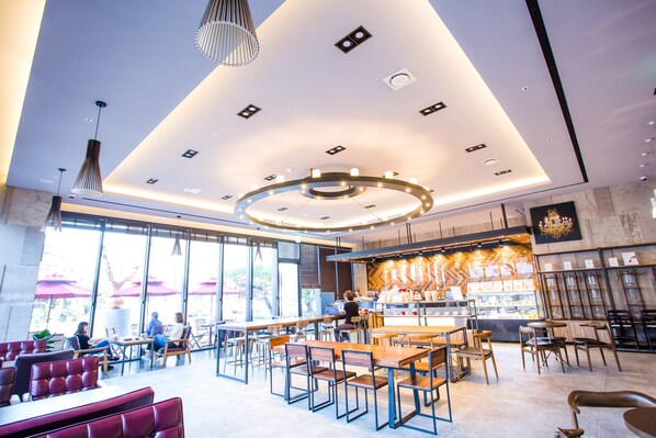 Un café moderno con barra central, zonas de estar y grandes ventanales.