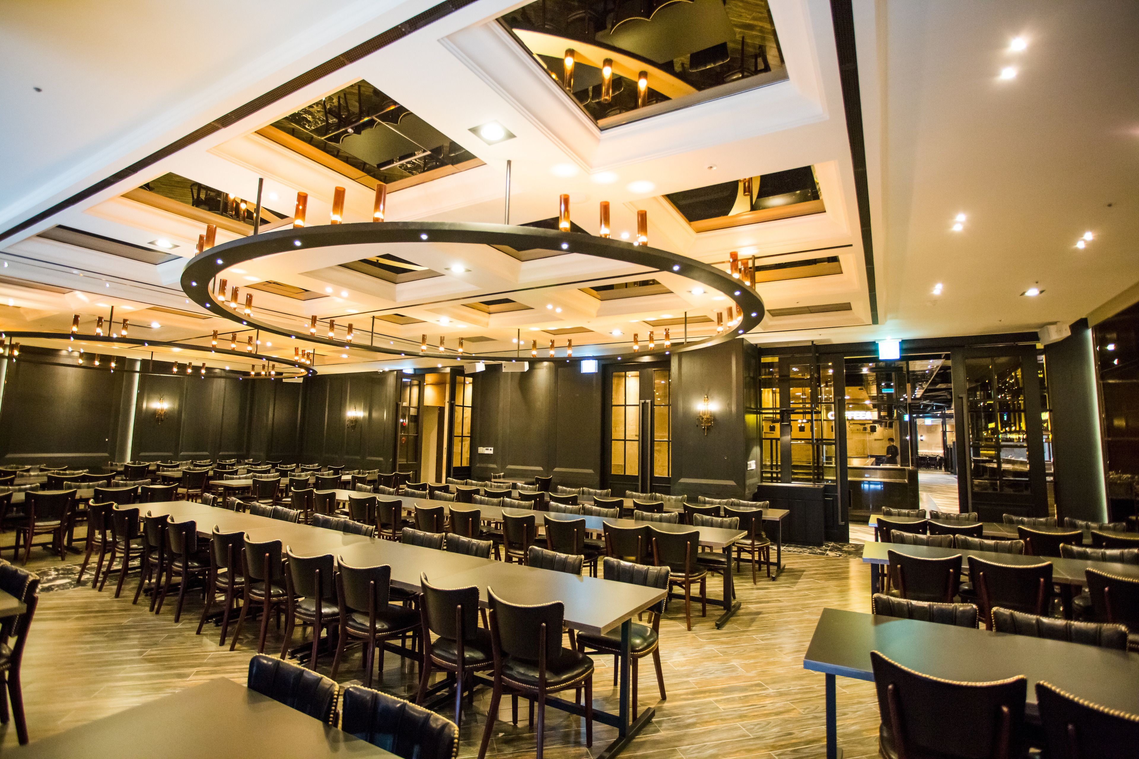 A large dining area with long tables and chairs, a circular ceiling design, and a modern interior.