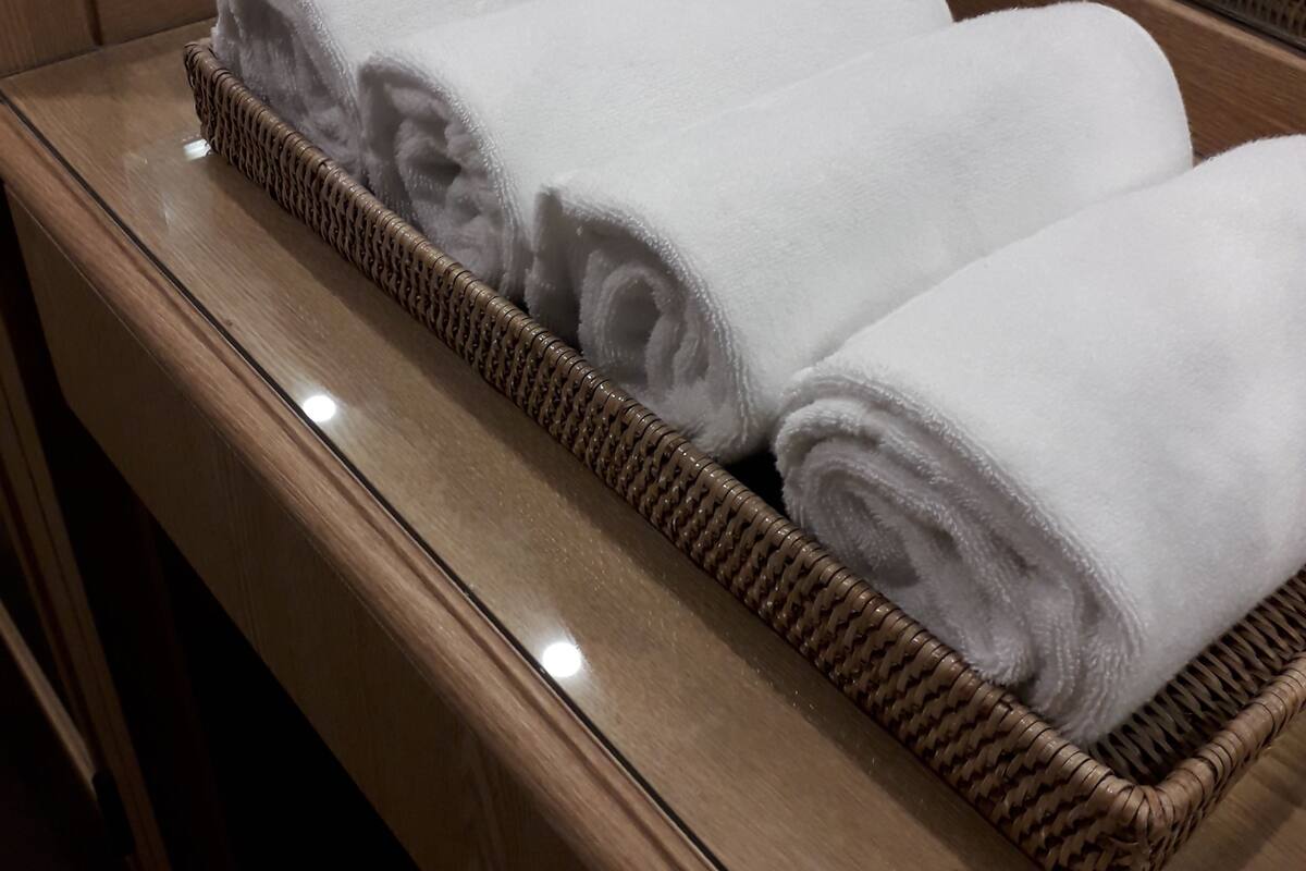 A wooden counter with three wicker baskets containing neatly folded white towels.