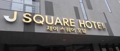 Un edificio con un letrero que dice “J SQUARE HOTEL” y texto coreano debajo.