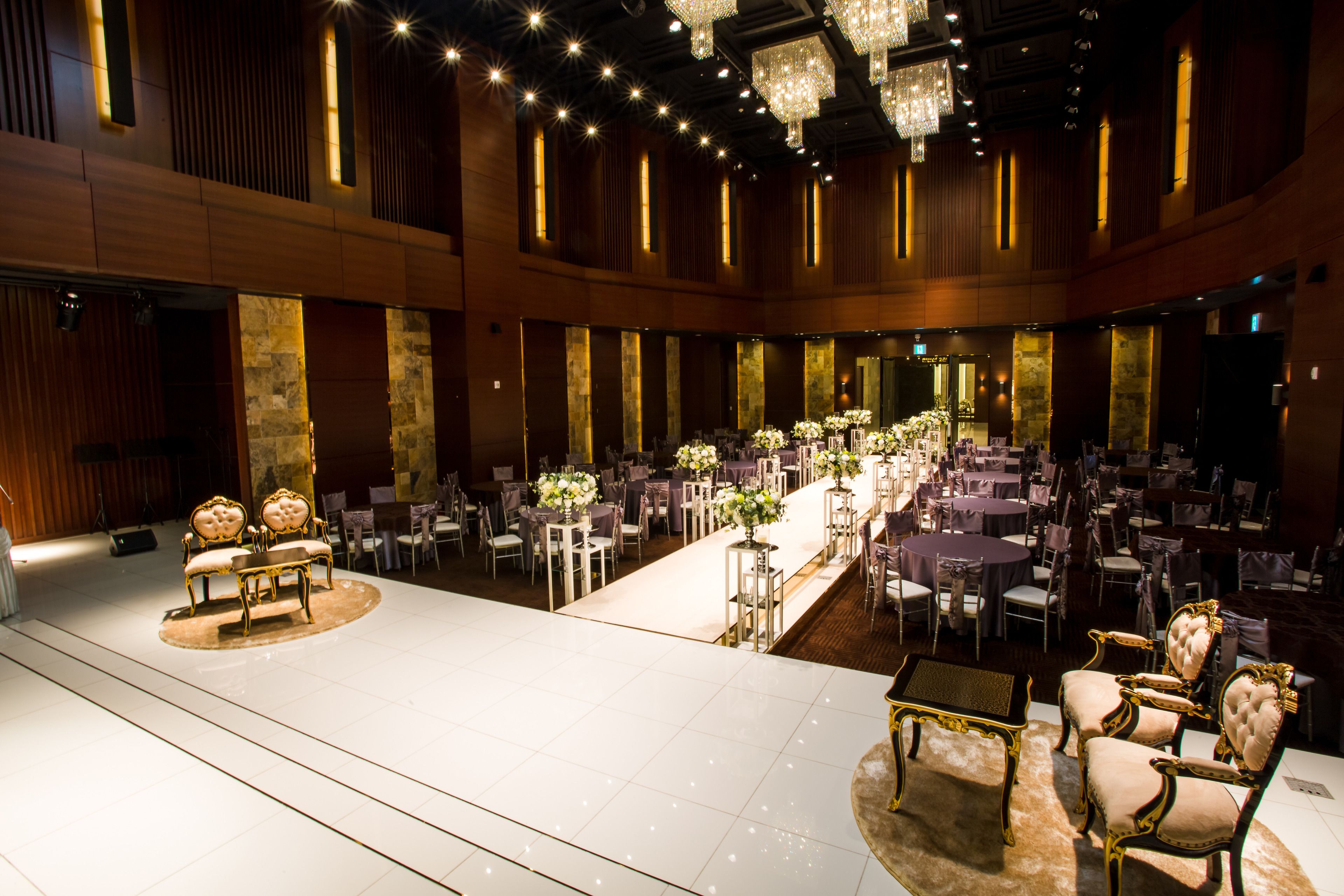A spacious banquet hall with a long table set for a formal event, surrounded by elegant chairs and chandeliers.