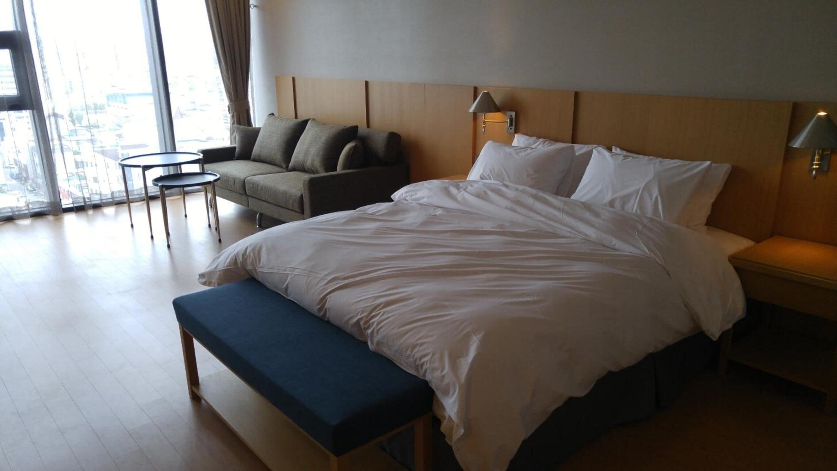 Una habitación de hotel con una cama grande, un banco, un sofá y una mesita.